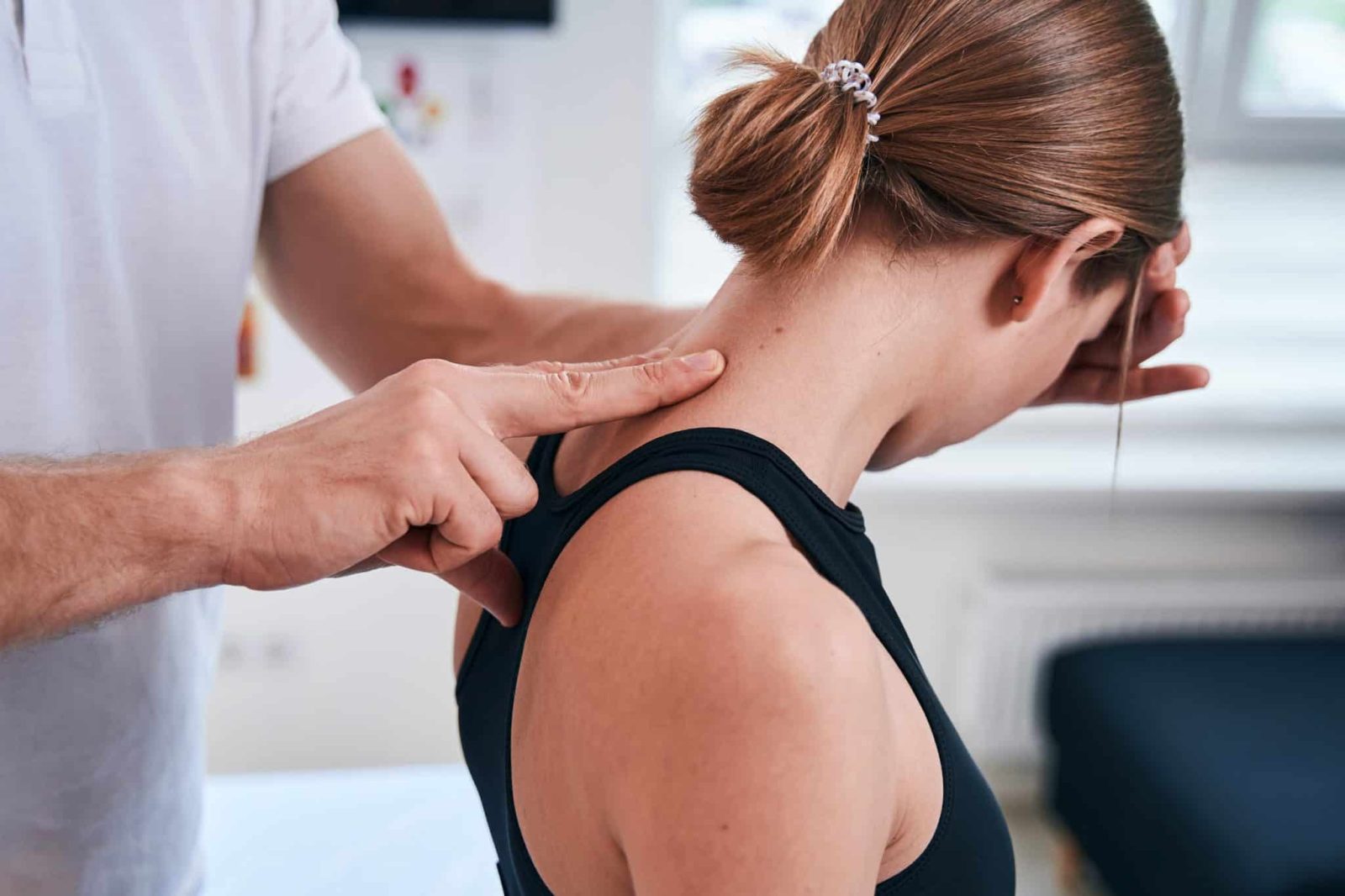 Kinesiology Near Me - Kinesiologist treating female patient's upper spine