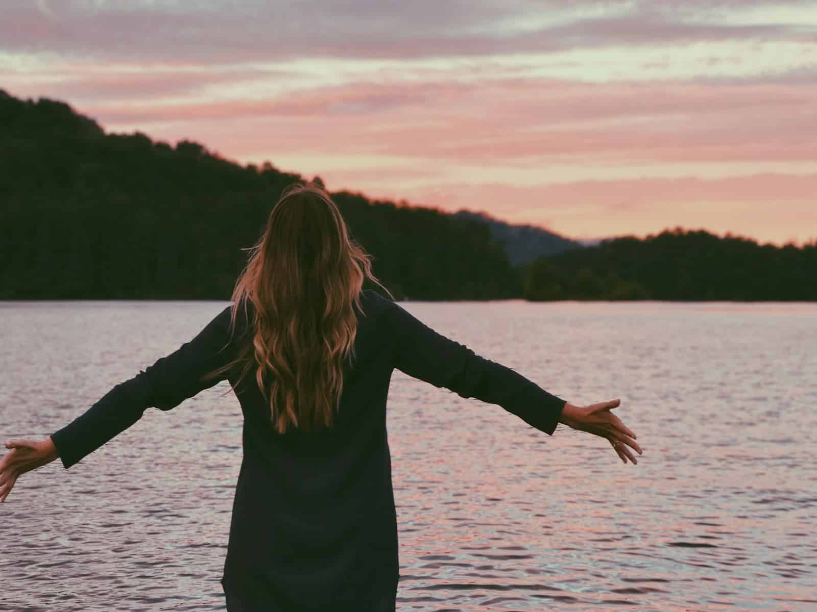 woman wearing black coat standing in front of the ocean. Psychosomatic Therapist Brisbane