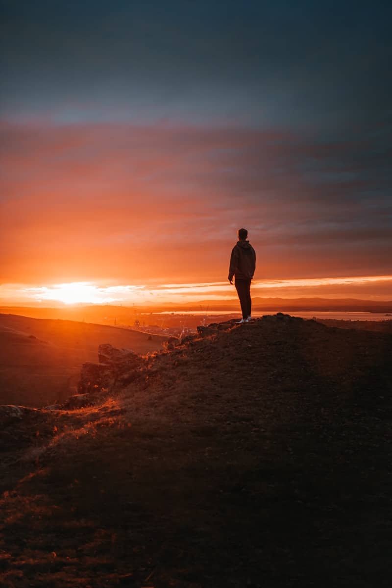 man in black jacket standing on brown rock during sunset. Mindset Therapy in Brisbane and around Australia