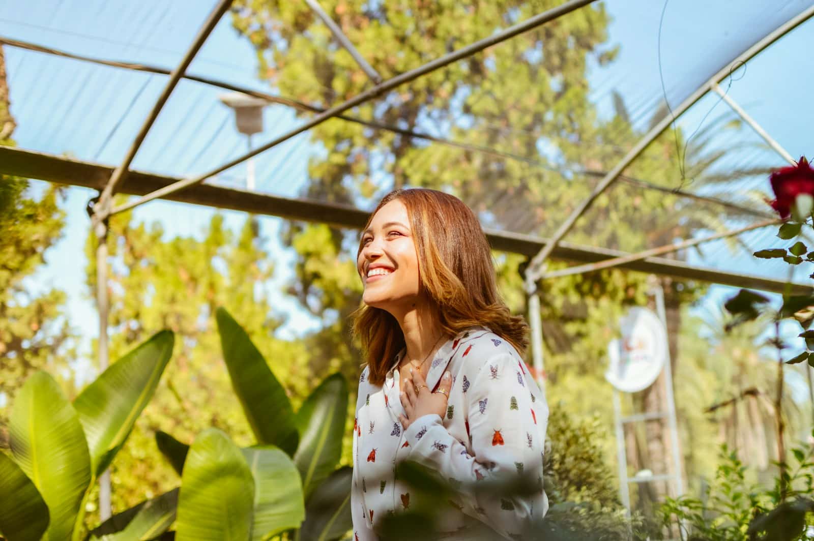 A woman standing in a greenhouse smiling after Mindset Therapy at Brisbane Livewell Clinic. Naturopath Redcliffe