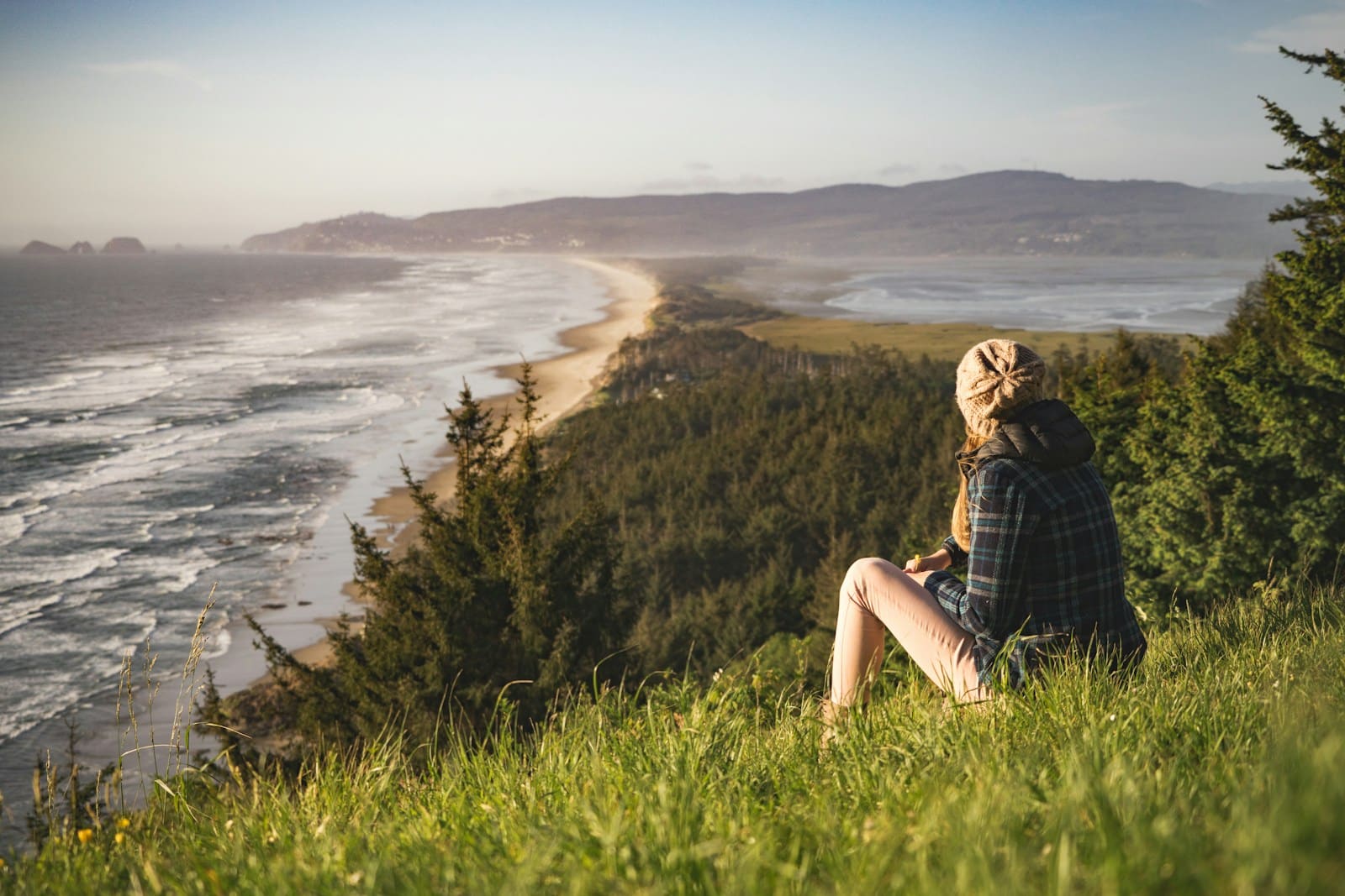 Person sitting on hill near ocean during daytime. Hypnotherapy for weight loss and does it work