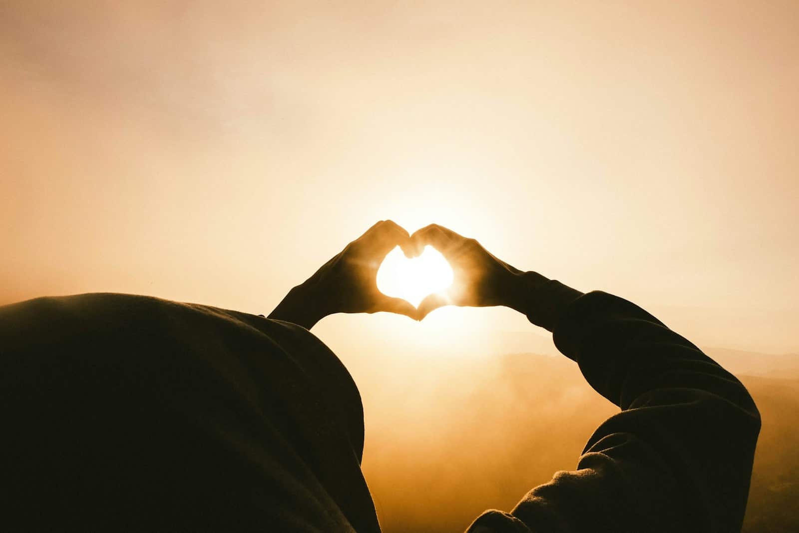 Person doing heart shape hand with sun light passing through. Emotional Resilience