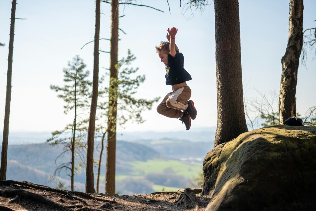 Child jumping in the air near some trees. Naturopath near me