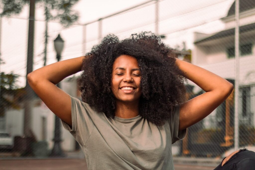 Woman with her hands on her head smiling. Therapeutic Massage Treatment. Massage Quiz