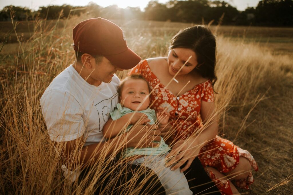 Man and woman sitting in a grass field with their baby. Naturopath near me.