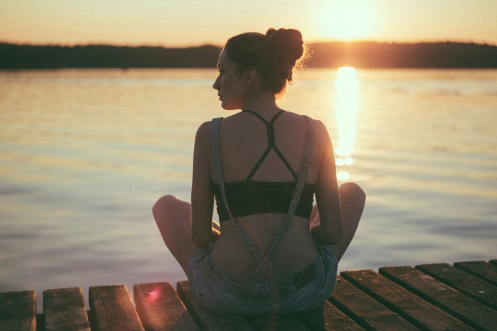 Woman sitting on a dock during sunset. Bowen Therapy Brisbane