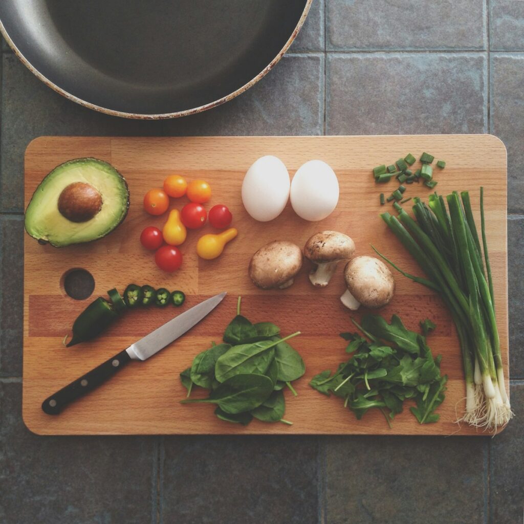 Breadboard with avocado, tomatoes, eggs, mushrooms, spring onions, and leaves. Dietitian Wavell Heights