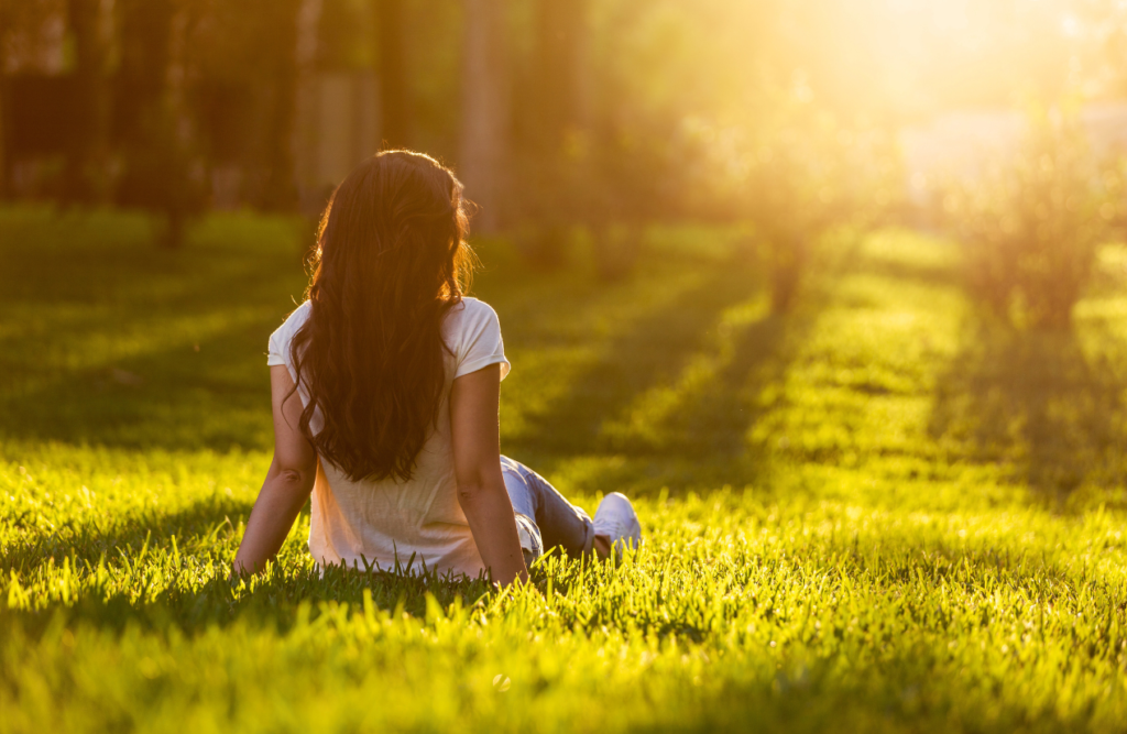 Woman sitting on the grass while enjoying the sunset. Swedish Massage Brisbane. Brisbane Livewell Clinic