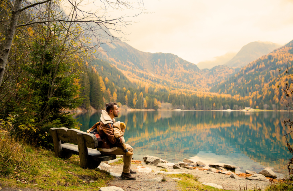 Father and child sit on a wooden bench near a lake. Thai Massage. Brisbane Livewell Clinic