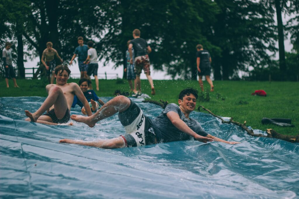 Group of men sliding on blue canopy after skilled Bowen professionals provide therapy