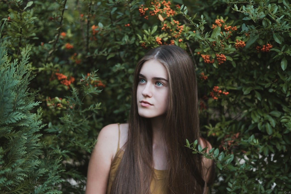 Teenage girl standing next to bushes with orange flowers. Youth Counselling Brisbane