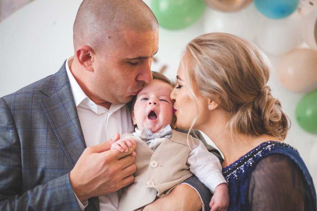 A man and woman holding a baby in front of balloons. Weight Loss Hypnosis Brisbane