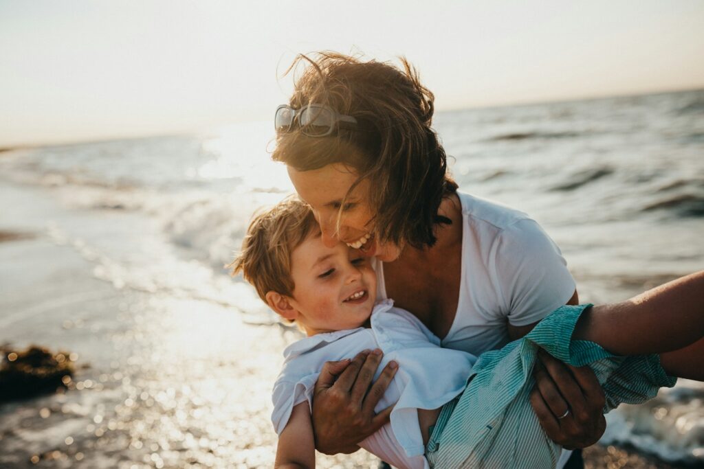 Mother holding child beside the ocean. Skilled Bowen professional