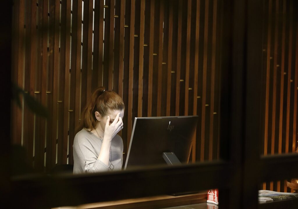 Woman sitting in front of a laptop computer with a headache. Heavy Metal Detox