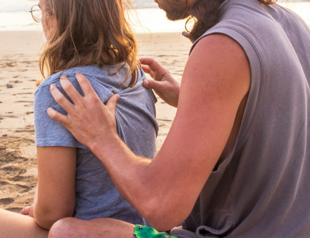 Skilled Bowen professional doing therapy on his partner at the beach