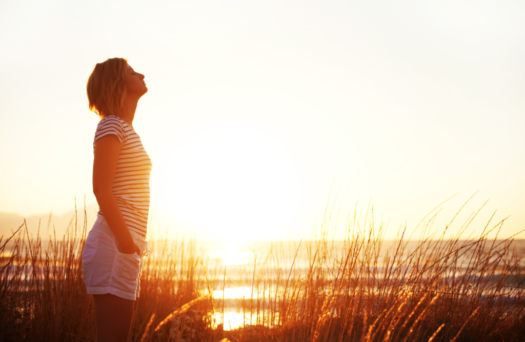 Woman standing on the field on a beautiful sunny day. Hypnotherapy Melbourne prices. Brisbane Livewell Clinic. Counselling Near Me