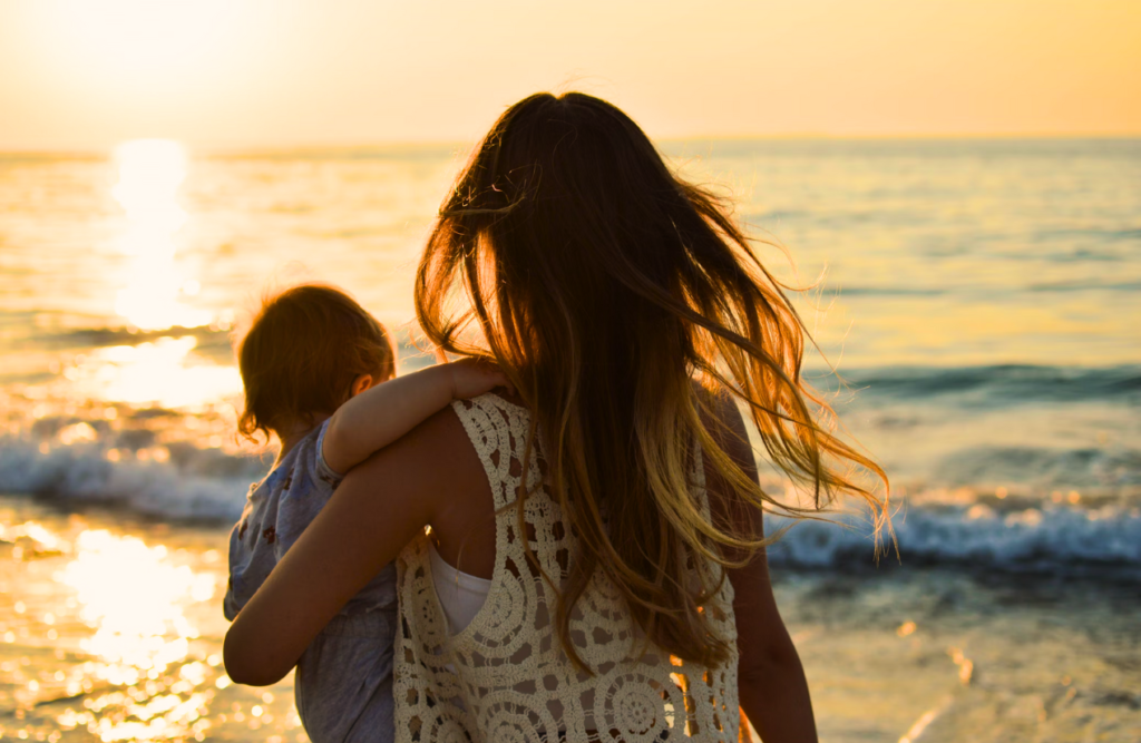 Monther is carrying her child while looking at the sunset. Acupuncture Queensland. Brisbane Livewell Clinic