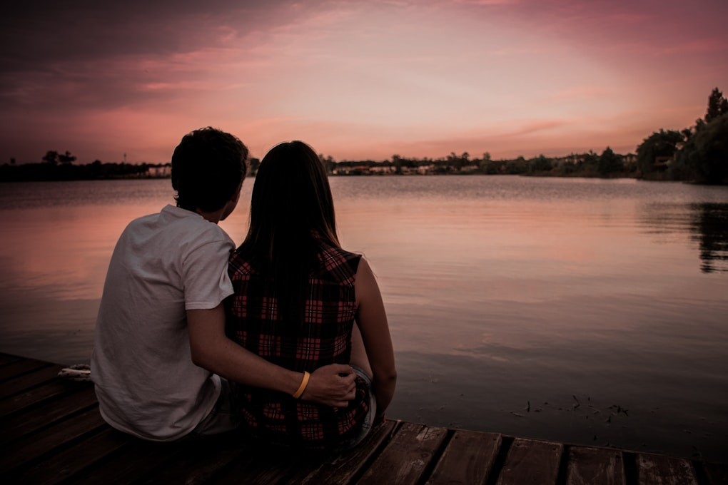 Man and woman sitting together on a dock at sunset after losing a loved one and suffering with grief. Counselling Near Me. Counselling Clayfield