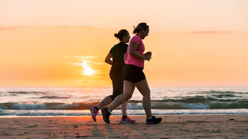 Two women running on beach at sunset. Hypnotherapy to Cease Smoking and Vaping