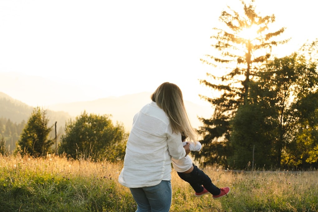 A woman holding a small child in a field. Hypnosis for Smoking Cessation. Hypnosis for Vaping Cessation