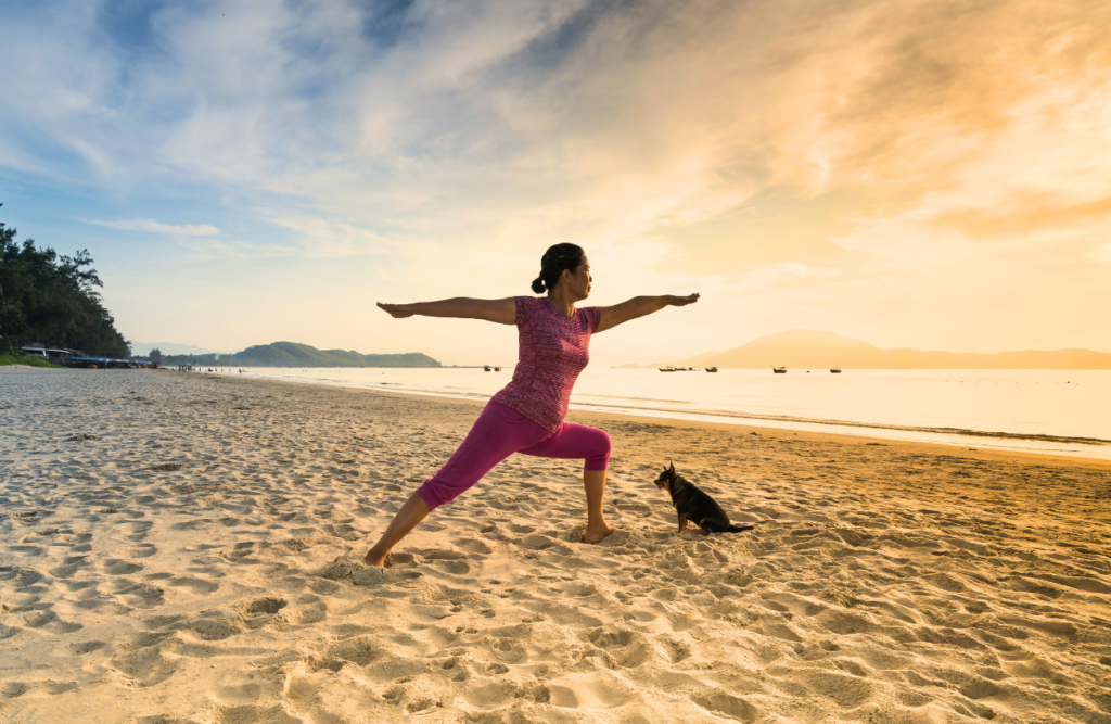 A woman practices yoga on a sandy beach at sunrise. Naturopath North Brisbane. Brisbane Livewell Clinic