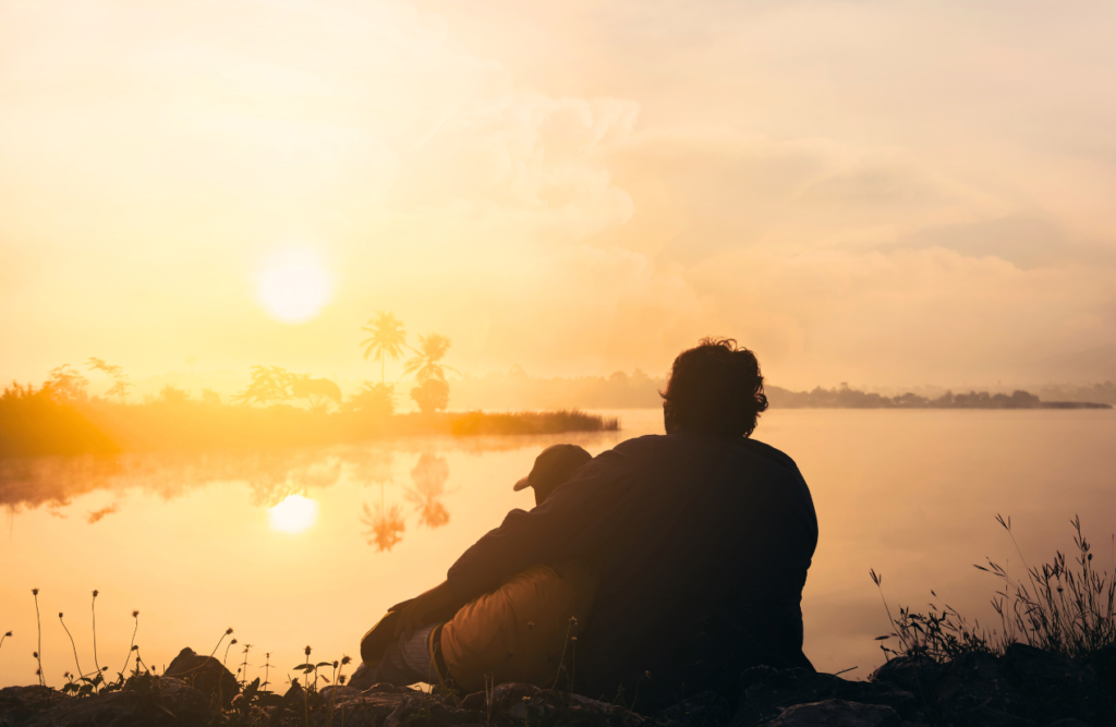 Silhouette of two people sitting on the grass beside body of water. Naturopath North Brisbane. Brisbane Livewell Clinic